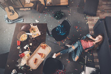 Top View Of Young Drunk Woman Lying On Floor In Messy Room