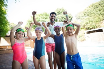 Wall Mural - Portrait of cheerful male instructor with little swimmers 