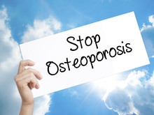 Stop Osteoporosis Sign On White Paper. Man Hand Holding Paper With Text. Isolated On Sky Background
