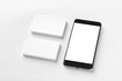 © Mayatnikstudio - Mockup of two blank horizontal business cards and black cell-phone at white textured paper background.