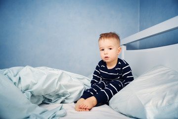 Wall Mural - Sleepy boy sitting in bed