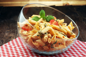 Wall Mural - Penne pasta in tomato sauce with chicken, tomatoes decorated with basil on a wooden table