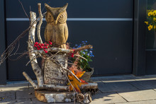 Wooden Owl Sits On A Wood Trunk With Ornaments And Flowers
