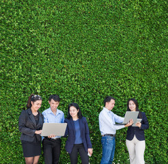 Businesswoman and businessman working outside office using laptop computer mobile phone and tablet device at green leaf wall,mobile office concept,copy space for adding text or design,Square banner