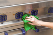Hand in protective glove with rag cleaning kitchen equipment in the professional kitchen. Stainless steel surface. Early spring cleaning or regular clean up.