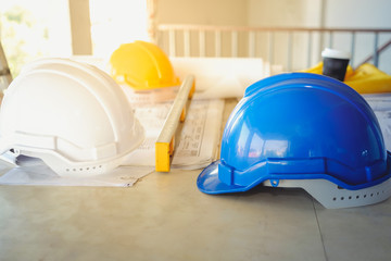 white, yellow and blue hard safety helmet hat for safety project of workman as engineer or worker on the table.