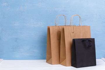 Mockup of blank shopping bags. Brown and black craft packages. Concept for sales or discounts. Recycled paper. Blue wooden rustic board.