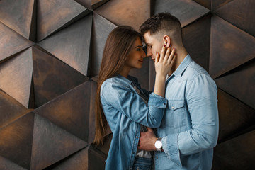 Young stylish couple in jeans clothes near a wooden vintage wall