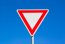 Give Way / Yield - Red And White Triangle. Clear Blue Sky Is Behind Road Sign.
