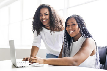 Two teen at desk in her office with laptop