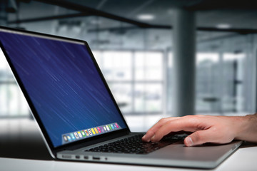 Hand typing on a keyboard of laptop with operating system screen on background