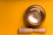 Metal Bowl With Wooden Stick On The Yellow Table On The Right