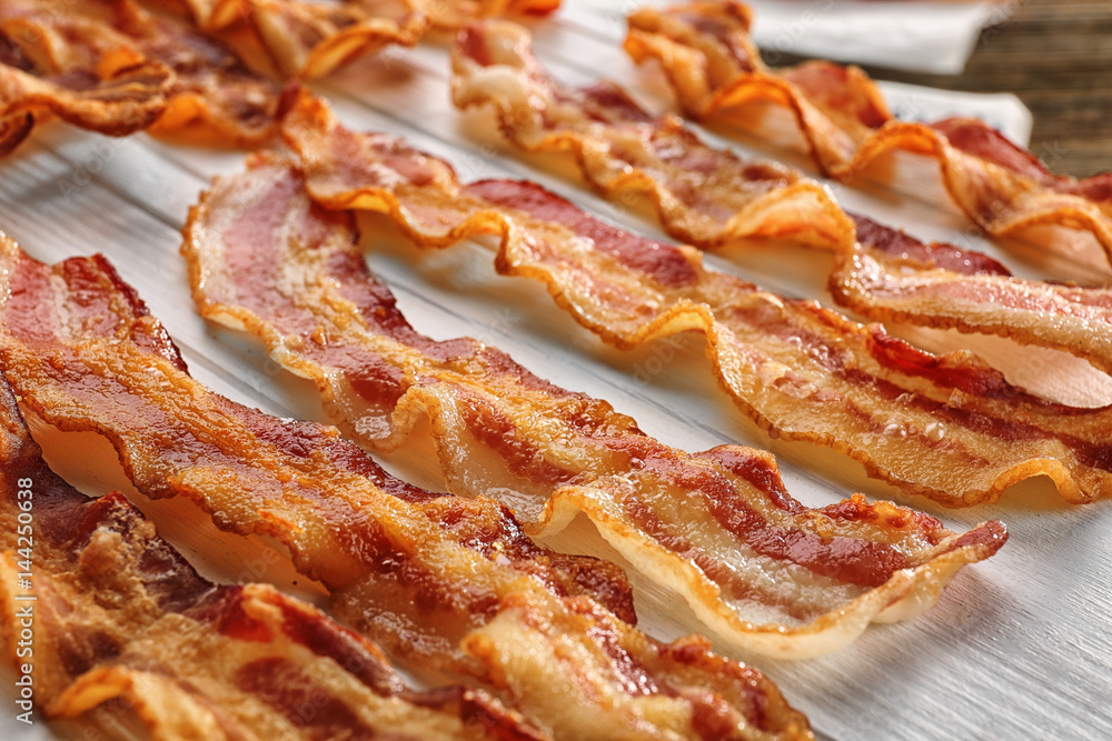 Wooden board with strips of fried bacon, closeup