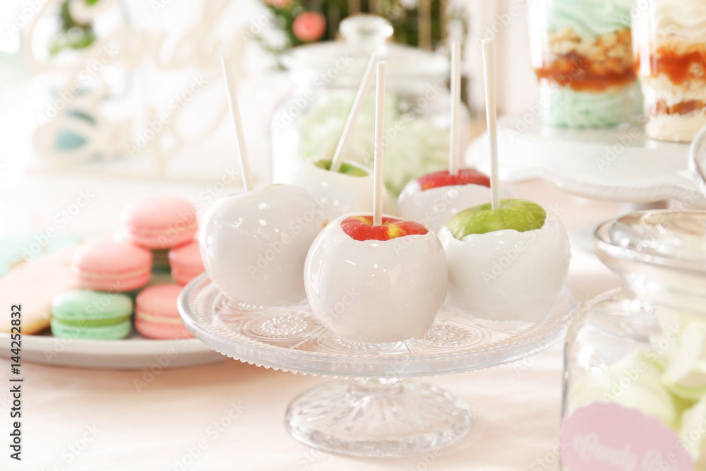 Vintage glass stand with candy apples on table