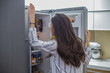 Morning scene. Smiling young woman in the kitchen in front of the refrigerator takes food and laughs