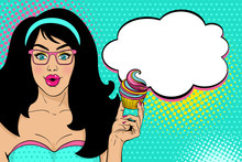 Wow Pop Art Female Face. Sexy Surprised Girl In Glasses With Long Black Hair, Open Mouth, Bright Cupcake In Her Hand And Speech Bubble. Vector Colorful Background In Pop Art Retro Comic Style.