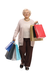 Wall Mural - Joyful mature woman with shopping bags walking towards the camera