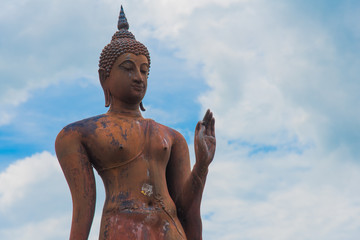 Buddha statue standing with cloudy sky background in Sukhothai historical park, Sukhothai province, Thailand