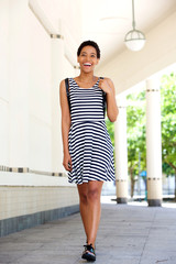 Wall Mural - happy young black woman in striped dress walking outside