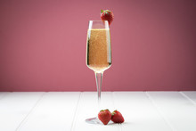 Champagne Sparkling White Wine Glass And Bottle On Plain Background With Strawberry Garnish Gold Ribbon