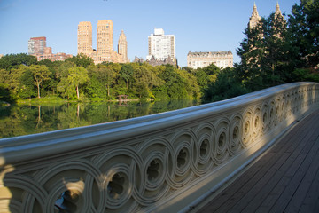 Wall Mural - Fence of Bow bridge over reflective lake at Central Park and buildings in Manhattan