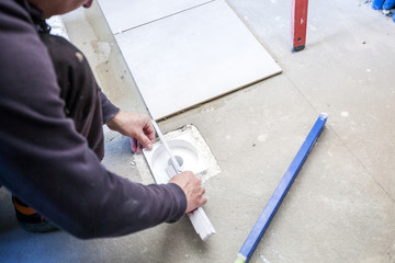 Man Tiling  Bathroom. Laying tiles on the floor