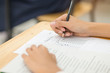 © smolaw11 - students hand holding pencil fill in Exam carbon paper sheet or test paper multichoice on wood desk, education concept