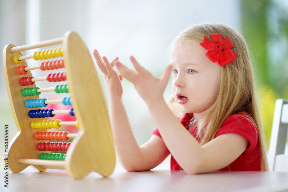 Cute little girl playing with abacus at home. Smart child learning to ...