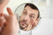 © Africa Studio - Young man putting contact lenses in front of mirror at home