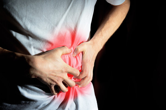 Fototapete - man, guy in a white t shirt on a black background hold hands on his stomach,  liver pain, pancreas, kidneys