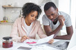 © Damir Khabirov - Young african american couple doing paperwork together, planning family budget, calculating domestic expenses, sitting at kitchen table with laptop and calculator at home. Financial problems concept