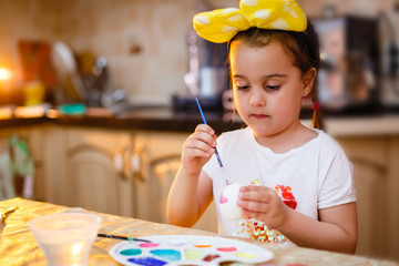 Wall Mural - Happy easter A beautiful child girl painting Easter eggs. Happy family preparing for Easter. Cute little child girl wearing bunny ears on Easter day.