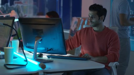  Young mixed ethnicity computer game design team working together in dark office. 