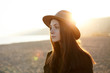 © WHstudio Leushin N - Portrait of pensive and melancholic European girl standing on seacoast in elegant demi-season outdoor clothes, dreaming, reminiscing good and important moments, evening sun kissing top of her head