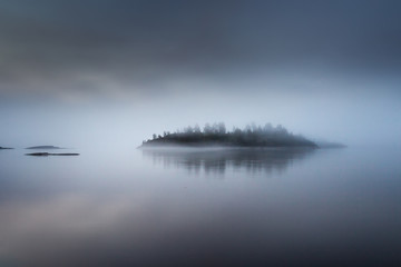 The island is in a fog. Karelia. Fog on the water.