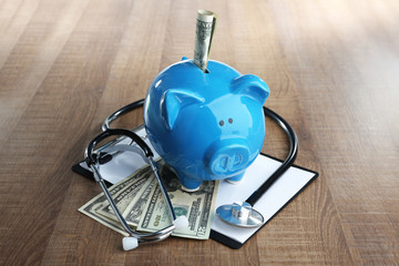 Poster - Piggy bank with stethoscope and clipboard on table