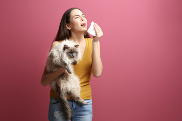 Animal allergy concept. Beautiful woman with cat on color background