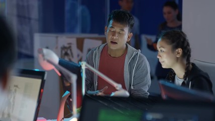  Game designers looking at computer screen & discussing ideas for the project