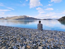 Man Sitting In Front Of Lake At Torres Del Paine