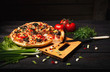 Fresh tasty pizza on black background on rustic wooden table with ingredients. Italian food.