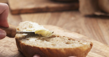 Female Teen Hand Spreads Butter On Slice Of Rustic Bread, 4k Photo