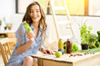 Beautiful woman sitting with healthy green food and drinks at home. Vegan meal and detox concept