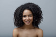 © Artem Varnitsin - Smiling woman with afro hairstyle standing at gray background in studio