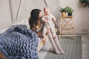 happy mother and baby playing at home in bedroom. Cozy family lifestyle in modern scandinavian interior.