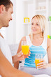 © Svetlana - Young couple looking at each other and holding glasses of orange juice.