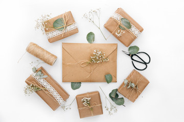 Canvas Print - Workspace. Wedding invitation cards, craft envelopes and flowers and green leaves on white background. Overhead view. Flat lay, top view