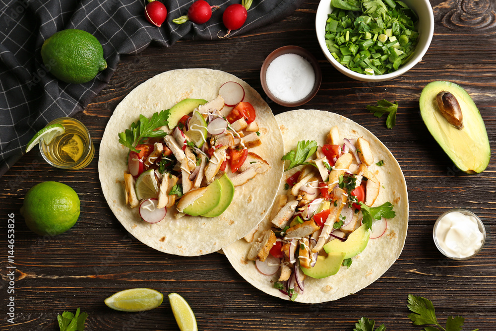 Tasty chicken tacos with tequila on table