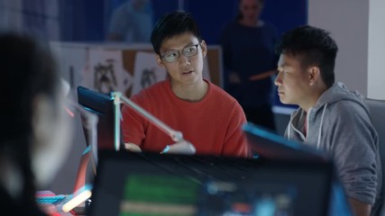  Game designers looking at computer screen & discussing ideas for the project