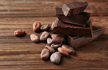 Canvas Print - Cocoa beans and pieces of chocolate on wooden background