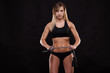 © satyrenko - Beautiful fitness woman is holding a skipping rope. Sporty girl showing her well trained body. isolated on dark background with copyspace